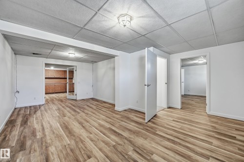 Interior space featuring wood-finish flooring, drop-tile ceilings, flush-mount lighting, and multi-panel doors - #19 10 Grange Dr, St. Albert, AB 