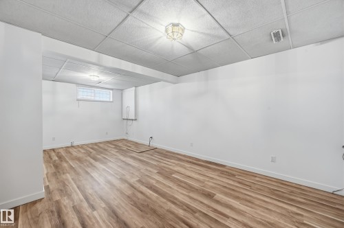Interior room featuring wood-finish flooring, white walls, drop ceiling, and recessed lighting fixtures - #19 10 Grange Dr, St. Albert, AB 
