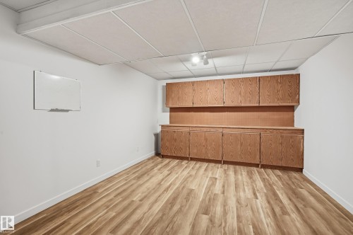 Wood-finish flooring, suspended ceiling, and extensive built-in wooden cabinetry featuring both upper and lower storage units - #19 10 Grange Dr, St. Albert, AB 