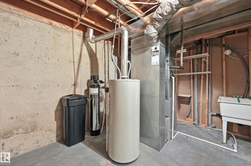 Mechanical room featuring a concrete foundation, water treatment system, cylindrical water heater, metal HVAC ductwork, and a wall-mounted utility sink - #19 10 Grange Dr, St. Albert, AB 