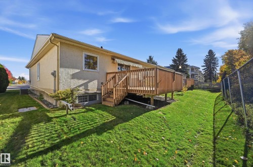 Exterior elevation with stucco siding, elevated wood deck, and grass-covered backyard enclosed by chain-link fencing - #19 10 Grange Dr, St. Albert, AB 