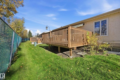 Raised wood deck with vertical balusters, fenced backyard, and manicured lawn - #19 10 Grange Dr, St. Albert, AB 