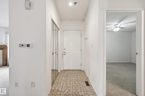 Entryway featuring stone-finish tile flooring, mirrored closet doors, and a paneled entry door - #19 10 Grange Dr, St. Albert, AB 