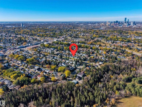 Aerial perspective of a residential lot situated within a mature neighborhood, featuring extensive surrounding tree canopy and a cityscape skyline on the horizon - 10226 72 St Nw, Edmonton, AB 