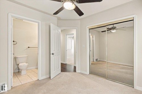 Ceiling fan, mirrored sliding closet doors, wall-mounted light fixture, white interior doors, and neutral carpet flooring - 771 Johns Road Nw, Edmonton, AB 