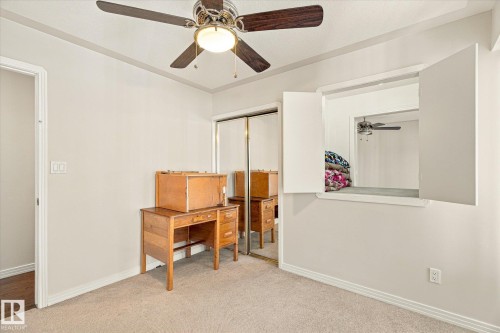 Ceiling fan with integrated lighting, mirrored closet doors, pass-through window with folding shutters, wall-to-wall carpeting, and painted walls - 771 Johns Road Nw, Edmonton, AB 