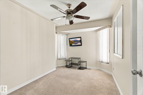 Tray ceiling with a ceiling fan, bay window with vertical blinds, and neutral carpeting - 771 Johns Road Nw, Edmonton, AB 
