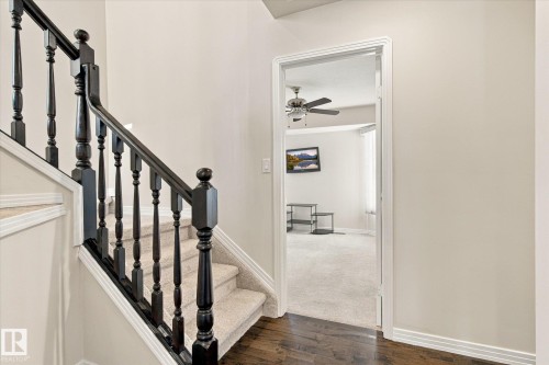 Hardwood flooring, painted banister, carpeted staircase, and neutral wall tones - 771 Johns Road Nw, Edmonton, AB 
