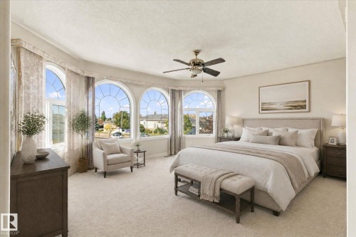 Arched bay windows with decorative grilles, ceiling fan with light fixture, light-toned carpeting, and neutral wall tones - 771 Johns Road Nw, Edmonton, AB 