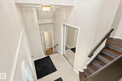 Dark wood-finish staircase with matching banister, light-toned wall paint, recessed lighting, and a mirrored closet door - 771 Johns Road Nw, Edmonton, AB 