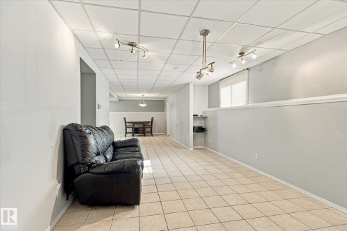 Expansive room featuring light-colored tile flooring, drop ceiling panels, recessed shelving, and multiple track lighting fixtures - 771 Johns Road Nw, Edmonton, AB 