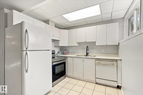 White cabinetry with matte black hardware, white appliances, stainless steel range, and tile flooring - 771 Johns Road Nw, Edmonton, AB 