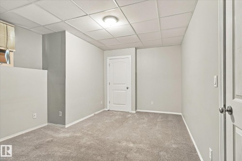 Plush gray carpeting, white painted walls, white paneled interior doors, and a drop ceiling with recessed lighting - 771 Johns Road Nw, Edmonton, AB 