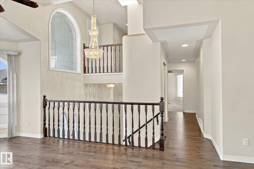 Multi-level interior featuring wood-finish flooring, a decorative chandelier, and an arched window - 771 Johns Road Nw, Edmonton, AB 