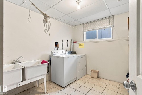 Utility room featuring a double-basin utility sink, tiled flooring, and a drop ceiling - 771 Johns Road Nw, Edmonton, AB 