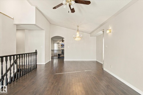 Vaulted ceilings, wood-finish flooring, chandelier, ceiling fan, and staircase with dark wood banister - 771 Johns Road Nw, Edmonton, AB 
