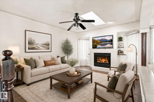 Living area featuring wood-finish flooring, a fireplace with a white surround, and a ceiling fan - 771 Johns Road Nw, Edmonton, AB 