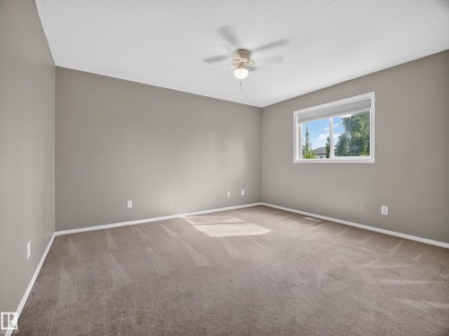 Neutral-toned walls with a white-framed window, overhead ceiling fan with lighting, and plush carpeting - 14 Wells Court, Leduc, AB 