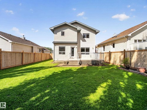 Expansive lawn area with a multi-level wood deck and full privacy fencing - 14 Wells Court, Leduc, AB 