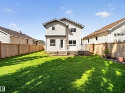 Expansive lawn area with a multi-level wood deck and full privacy fencing - 