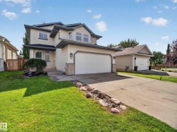 Two-story exterior with light-toned siding, attached two-car garage, concrete driveway, and a manicured lawn - 