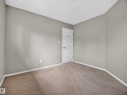Neutral wall paint, plush carpet flooring, white trim, and a white interior door - 