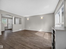 Spacious main living area featuring wood-finish flooring, neutral paint palette, ample natural light from large windows, and an arched entry - 
