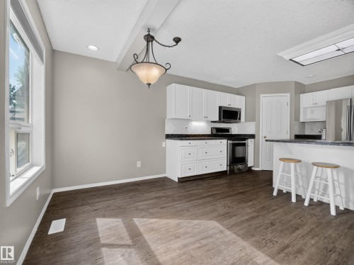 Spacious dining area with wood-finish flooring, recessed lighting, and a decorative ceiling fixture - 14 Wells Court, Leduc, AB 