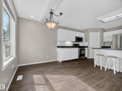 Spacious dining area with wood-finish flooring, recessed lighting, and a decorative ceiling fixture - 
