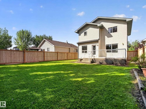 Expansive lawn with a full privacy fence, elevated wood deck, and a wood lattice skirt - 14 Wells Court, Leduc, AB 