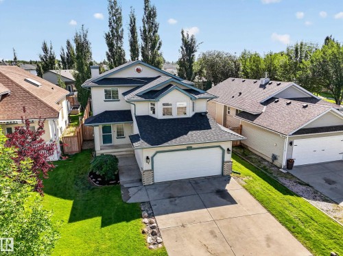 Two-story residence featuring a two-car garage, concrete driveway, and established landscaping - 14 Wells Court, Leduc, AB 