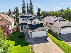 Two-story residence featuring a two-car garage, concrete driveway, and established landscaping - 