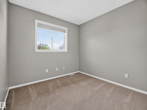 Carpeted flooring, neutral wall color, white trim, and a window with white casing - 14 Wells Court, Leduc, AB 