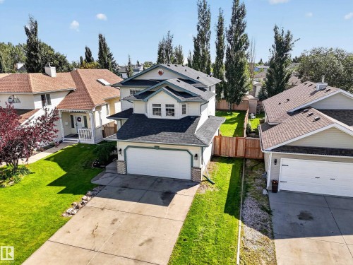 Two-story home with a two-car garage, concrete driveway, and a fenced backyard with a manicured lawn - 14 Wells Court, Leduc, AB 