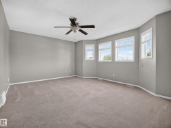 Spacious room with a ceiling fan, light gray wall paint, multiple windows with blinds, and beige carpeting - 