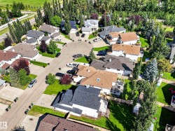 Residential properties featuring various roof styles, mature trees, and landscaped yards - 