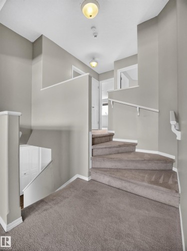 Carpeted staircase with white handrails and neutral wall paint - 14 Wells Court, Leduc, AB 