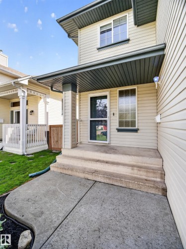 Siding exterior with a covered porch entry featuring a column, concrete steps, and a concrete pathway - 14 Wells Court, Leduc, AB 