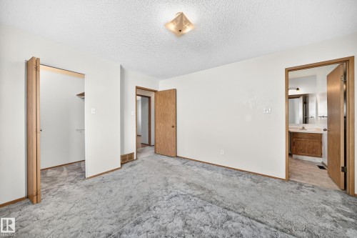 Carpeted room with a ceiling-mounted light fixture, bi-fold closet doors, and wood-finish trim - 14519 32 Street Nw, Edmonton, AB 