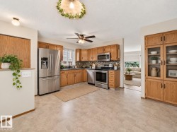 Kitchen featuring wood cabinetry, stainless steel appliances, mosaic tile backsplash, and durable tile flooring - 