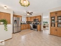 Kitchen featuring wood cabinetry, stainless steel appliances, mosaic tile backsplash, and durable tile flooring - 14519 32 Street Nw, Edmonton, AB 