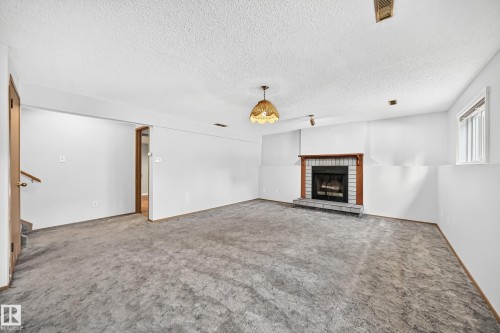 Spacious living room featuring neutral carpet flooring, white walls, and recessed lighting - 14519 32 Street Nw, Edmonton, AB 