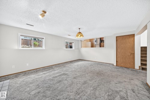 Spacious recreation room featuring neutral wall finishes, recessed lighting, and abundant natural light from dual windows - 14519 32 Street Nw, Edmonton, AB 