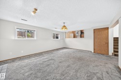Spacious recreation room featuring neutral wall finishes, recessed lighting, and abundant natural light from dual windows - 