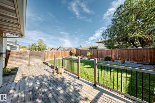 Expansive backyard featuring a large wooden deck, manicured lawn, and privacy fencing - 14519 32 Street Nw, Edmonton, AB 