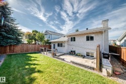 Expansive backyard featuring a manicured lawn, a large wood deck, and a full privacy fence - 