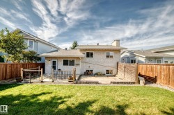 Expansive backyard featuring a manicured lawn, a multi-level patio, and a privacy fence - 