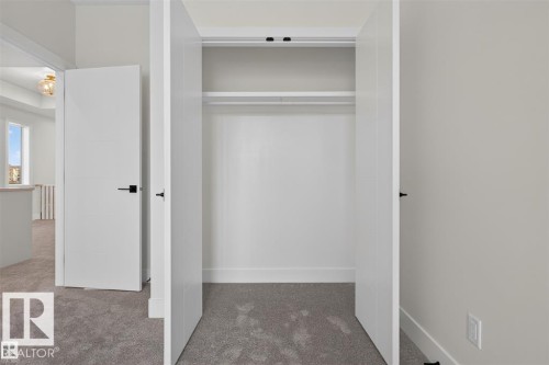 Built-in closet with two clothing rods and shelving, modern flat-panel doors, matte black hardware, and gray carpeting - 101 Rosa Crescent, St. Albert, AB 