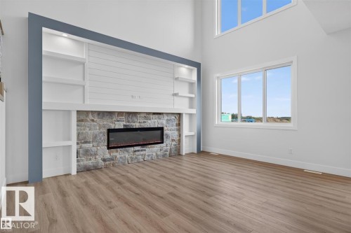 Stone-clad fireplace with an electric insert, integrated shelving, and accent lighting - 101 Rosa Crescent, St. Albert, AB 