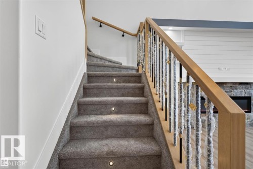 Carpeted staircase with integrated step lighting and wood-finish handrail - 101 Rosa Crescent, St. Albert, AB 